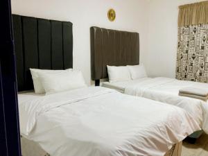 路易特里哈特The Plum的配有白色床单的酒店客房内的两张床
