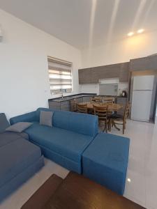 安曼Airport house的一间带蓝色沙发的客厅和一间厨房