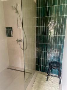 厄里圣彼得Patika Vendeghaz的浴室铺有绿色瓷砖,配有带凳子的淋浴
