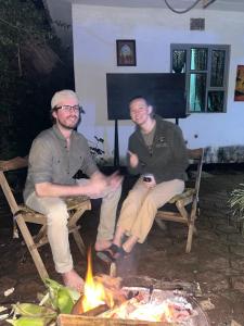 阿鲁沙Meleji studio room的两个男人坐在火炉旁的椅子上