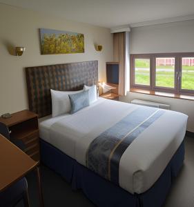 拉格比金狮酒店的酒店客房设有一张大床和一张书桌。