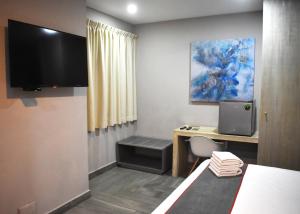 普拉亚卡门Attraction Hotel Deluxe的小房间设有书桌和电视