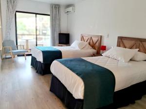 拉塞雷纳Hotel Palmas de La Serena的酒店客房设有两张床和窗户。