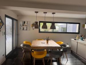 La Guerche-de-BretagneJolie maison avec piscine et Spa的一间带木桌和黄色椅子的用餐室