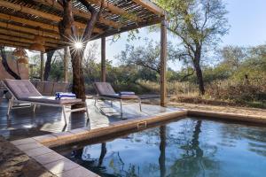 斯库库扎Rixile Kruger Lodge的一个带两把椅子的庭院和一个游泳池