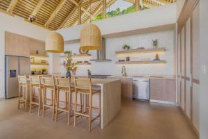DominicalitoCasa Frenchie Luxury Oceanview Jungle Villa for 12 people的一个带大岛的厨房,配有椅子和桌子