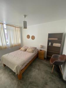 帕拉卡斯Killamoon House Paracas的一间卧室配有一张床和一把椅子