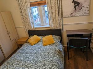 伦敦London Central Large Acton House的一间卧室配有一张带黄色枕头的床和一扇窗户