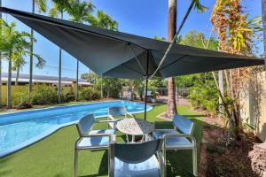 达尔文帕拉维斯塔汽车旅馆的游泳池旁配有遮阳伞的桌椅