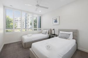 黄金海岸阿丽斯公寓酒店的配有2张床的白色墙壁和窗户客房