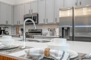 奥兰多Paradiso Brand New Top Elegance Vacation Home 6086的厨房配有白色橱柜以及带杯子和餐具的盥洗池