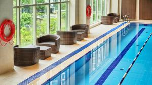 首尔LOTTE City Hotel Mapo的一座带藤椅的游泳池和一座游泳池
