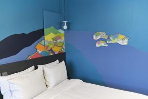 首尔卡布奇诺酒店的卧室配有一张床,墙上挂有绘画作品