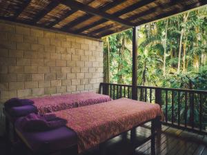 帕洋安巴厘岛空中花园别墅的门廊配有两张床,阳台种有树木