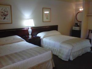 圣何塞Caravelle Inn Extended Stay的酒店客房,设有两张床和一盏灯
