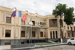 撒马尔罕Ko'k Saroy Plaza Hotel的前面有三面旗帜的建筑