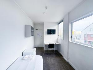 惠灵顿140 Ghuznee Hostel的一间卧室配有一张床、一张书桌和一个窗户。