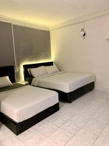 哥打巴鲁Andiana Hotel & Lodge - Kota Bharu City Centre的配有白色床单的酒店客房内的两张床