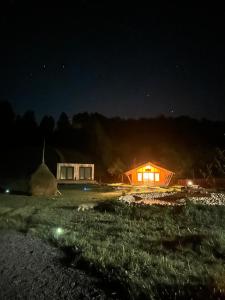 BăniţaRai Village的夜晚的小屋有灯光,山底下有山
