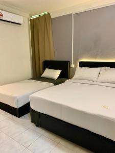 哥打巴鲁Andiana Hotel & Lodge - Kota Bharu City Centre的配有两张床的酒店客房中的两张床
