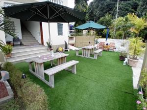 普拉兰La Residence D'Almee Guesthouse的庭院设有两张野餐桌和一把雨伞。