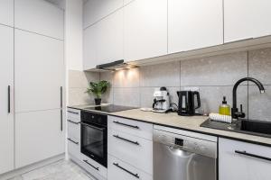华沙Cayenne Premium Apartment Airport的厨房配有白色橱柜和不锈钢用具