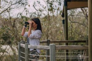 雾观Mdluli Safari Lodge的一位用相机拍栅栏照片的妇女