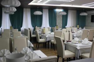 诺亚布尔斯克Hotel Rossiya的一间设有白色桌椅和绿色窗帘的餐厅