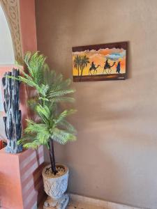 梅尔祖卡Riad Merzouga Dunes的画旁的花瓶里棕榈树