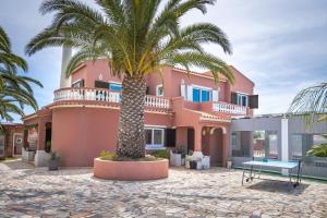 佩拉Villa Paradis - Quartos的粉红色房子前面的棕榈树