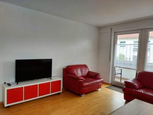 HardtGästehaus Walter的客厅配有2把红色椅子和平面电视