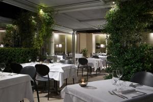 马拉内罗洛坎达拉卡泽拉酒店的一间设有白色桌椅的餐厅,种植了植物