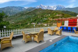达兰萨拉juSTa Birding Resort & Spa - Best Dhauladhar View Resort的游泳池旁带桌椅的天井