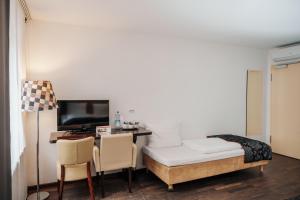 慕尼黑慕尼黑城中心赫尔维蒂亚酒店的客房设有书桌、床和电视。