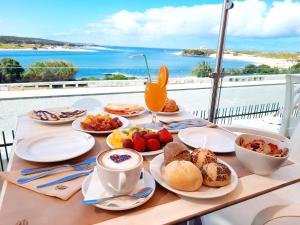 米尔芳提斯城Hotel HS Milfontes Beach - Duna Parque Group的一张带早餐食品的桌子,享有海景