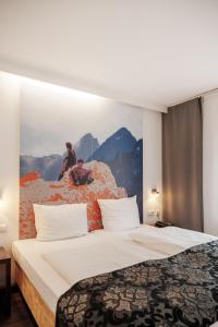 慕尼黑慕尼黑城中心赫尔维蒂亚酒店的酒店客房的墙上设有一张带绘画的床铺。