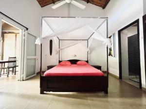 贝岛Résidence Kambana的一间卧室配有一张带红色床单的天蓬床