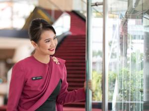 雅加达铂尔曼雅加达印尼酒店的穿着紫色毛衣的女人看着窗户
