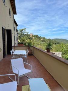潘札诺Terrazza a Campana的设有一个配有白色桌椅的阳台,享有美景。
