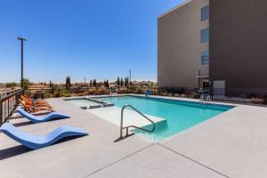 埃尔帕索La Quinta Inn & Suites by Wyndham El Paso East Loop-375的一座带两把躺椅的游泳池以及一座建筑