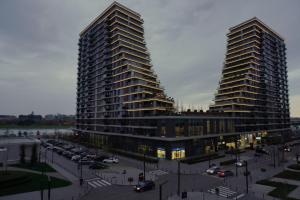 贝尔格莱德Belgrade Waterfront Comfortable Apartment的两座高楼,旁边是停车场,有车