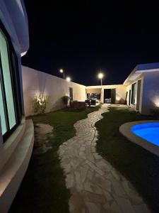 利雅德HAFAL Resort شاليهات هافال的一座房子的后院,晚上有一座游泳池