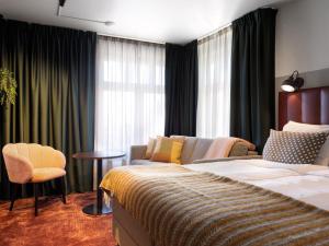 厄勒布鲁厄勒布鲁城市酒店的一间卧室配有一张床、一张沙发和一把椅子