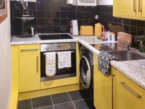 绍斯波特The Hideaway的黄色的厨房设有水槽和洗衣机