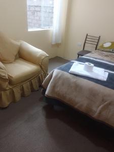 普诺killa andina inn的一间卧室配有一张床、一张沙发和一把椅子