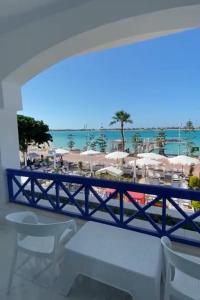 阿莱曼premium sea porto marina suite的阳台享有海滩美景,配有椅子和遮阳伞