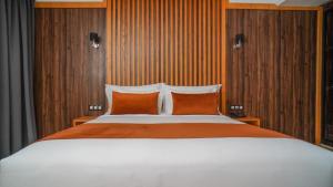 盖尼特拉Razane Hôtel的一间卧室配有一张大床和两个橙色枕头