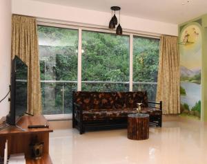 波戈马洛Ranghavi sands Apartment with Pool - near beach and Dabolim Airport的客厅在大窗户前配有沙发