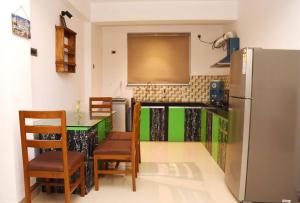 波戈马洛Ranghavi sands Apartment with Pool - near beach and Dabolim Airport的厨房配有冰箱和桌椅