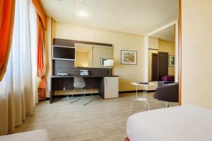 博洛尼亚JR Hotels Bologna Amadeus的酒店客房带一张床、一张桌子和椅子